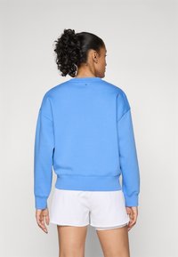 Sweatshirt azul claro com um ajuste descontraído, gola redonda e punhos canelados. Feito de um tecido suave, apresenta um design simples e de cor sólida.