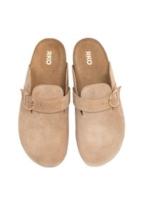 Beżowe zamszowe clogs z okrągłym noskiem, otwartym tyłem oraz dekoracyjnym paskiem z srebrną klamrą. Wnętrze ma miękką teksturę.
