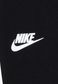 Crni materijal s istaknutim bijelim Nike logotipom i zakrivljenim swoosh dizajnom, pokazuje glatku teksturu i jednostavno, odvažno brendiranje.