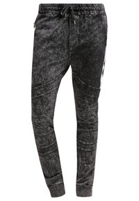 Černé joggingové kalhoty s texturovaným, vybledlým vzhledem. Mají stahovací pas, žebrované manžety a prošité detaily pro sportovní vzhled.