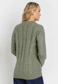 Olivgrön stickad tröja med kabelmönster, rund halsringning och ribbad kant. Långa ärmar med texturerad detaljering.