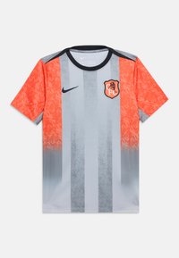 Αθλητική φανέλα με κοντά μανίκια, κατακόρυφες γκρι ρίγες, φωτεινά πορτοκαλί μανίκια, μαύρο γιακά, λογότυπο της Nike και έμβλημα με λιοντάρι και τα γράμματα "CFC".