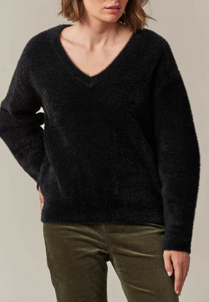 Pull noir, moelleux, avec un col en V et une coupe ample. Doté de manches longues et d'une texture douce. Assorti à un pantalon vert olive.