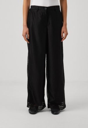 Pantalons larges noirs en tissu en maille léger et respirant, avec un motif en damier texturé et des fentes latérales pour la ventilation.