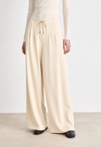 Beige videbukser laget av myk stoff, med elastisk midje og snor. Designet har en avslappet passform og jevn tekstur.