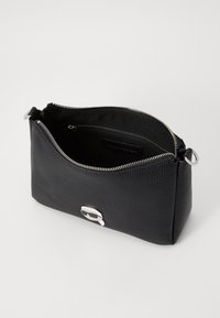 Borsa nera in pelle texture con chiusura a zip. Presenta hardware in argento e una tasca interna. Forma rettangolare compatta.