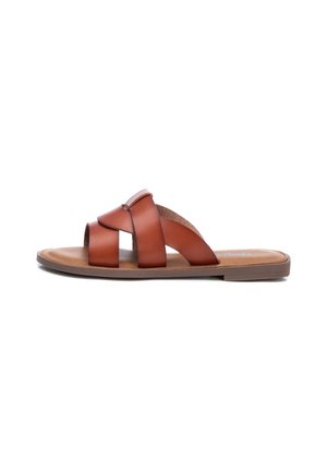 Brun læder flad slip-in sandal med tre brede remme, der krydser toppen, og en lav hæl på hvid baggrund.
