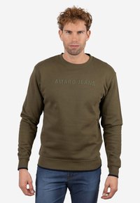 Sudadera verde oliva con cuello redondo acanalado, mangas largas y texto "AMARO JEANS" en un color a juego ligeramente en relieve. Textura suave.