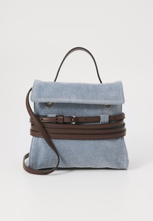 Zaino in denim blu con una forma strutturata, dotato di cinghie in pelle marrone avvolte attorno al corpo e di una maniglia superiore.