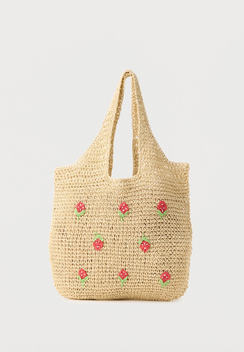 Μπεζ υφασμάτινη τσάντα ώμου με κοντές λαβές, διακοσμημένη με μικρά κόκκινα και πράσινα κεντημένα λουλούδια διασκορπισμένα στην πρόσοψη.