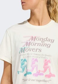 Witte katoen T-shirt met een kleurrijke grafische bedrukking met "Monday Morning Movers," oefenillustraties en tekstdetails in pastelkleuren.