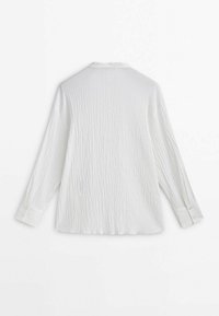 Chemise blanche à manches longues avec tissu texturé, design légèrement froissé, col pointu et poignets à boutons.