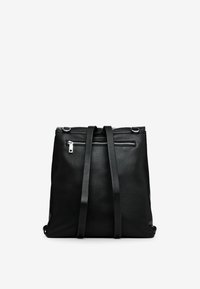 Musta nahkainen reppu, jossa on säädettävät remmit, teksturoitu pinta ja etutasku vetoketjulla. Varustettu hopeisilla metalliosilla ja minimalistisella muotoilulla.