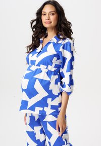 Blauw-wit gemusterde zwangerschapsblouse met een kraaghals, gathered taille en driekwart mouwen, gemaakt van lichtgewicht stof.