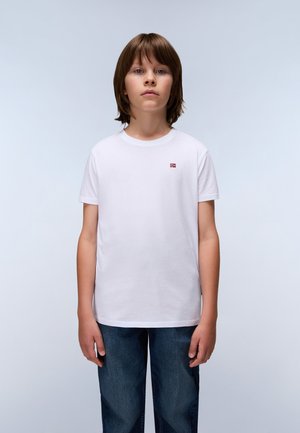Weißes Baumwoll-T-Shirt mit Rundhalsausschnitt, kurzen Ärmeln und einem kleinen roten und blauen Flaggenemblem auf der linken Brust. Trägt man mit blauen Jeans.