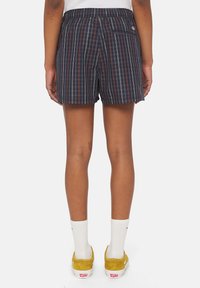 Pantalones cortos de cuadros en azul marino con una cintura elástica, con rayas rojas y blancas. Incluye un bolsillo trasero, diseño ligero y casual.