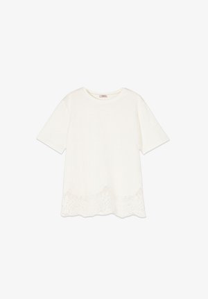 Bílá krátký rukávová halenka s kulatým výstřihem a zdobeným krajkovým lemem, zobrazena na jednoduchém bílém pozadí.