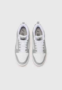 Grå og hvide sneakers med en tekstureret overdel, perforeret tåboks, flade hvide snørebånd og en hængslet rem på bagsiden. Logo på tungen.