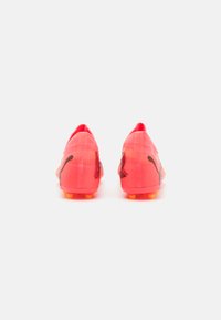 Botas de fútbol de color rosa brillante con un upper texturizado, acentos negros y tacos amarillos en la suela. Diseño aerodinámico y elegante para un mejor rendimiento.
