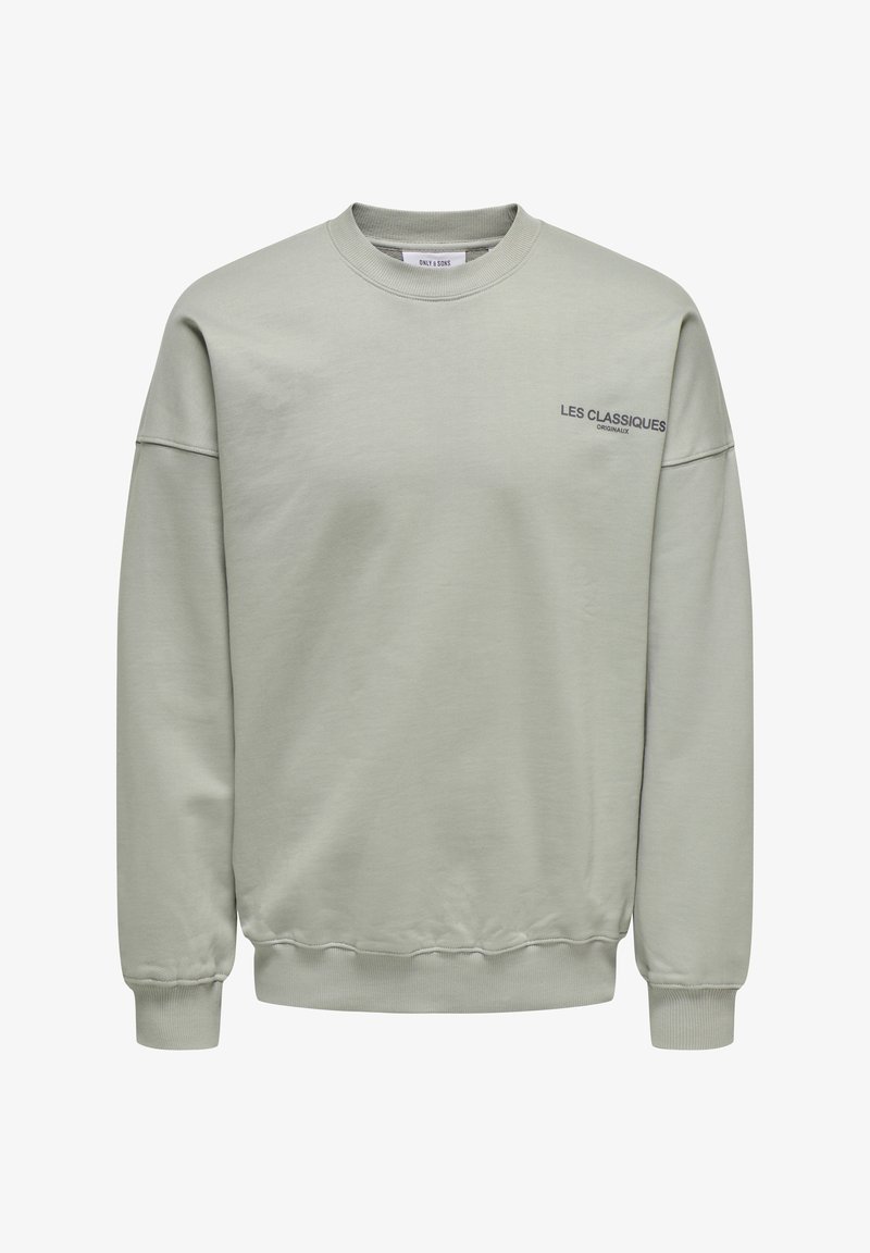 Light grey sweatshirt with a crew neck, ribbed cuffs, and hem. Features a printed text detail “LES CLASSIQUES” in dark blue on the front.