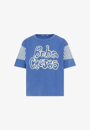 T-shirt blu a maniche corte con scritta bianca ondulata "Bobo Choses" sul davanti e strisce verticali bianche sulle parti superiori delle maniche.