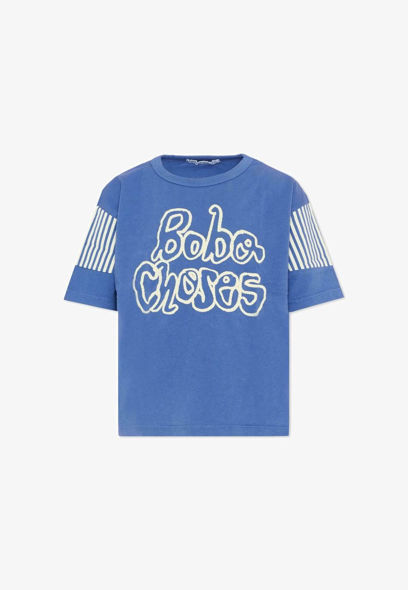 T-shirt bleu à manches courtes avec le texte ondulé blanc "Bobo Choses" sur le devant et des rayures verticales blanches sur le haut des manches.