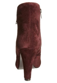 Burgundské semišové kotníkové boty s elegantním designem, vysokým jehlovým podpatkem a zipem vzadu. Hladký povrch, žádné viditelné vzory.
