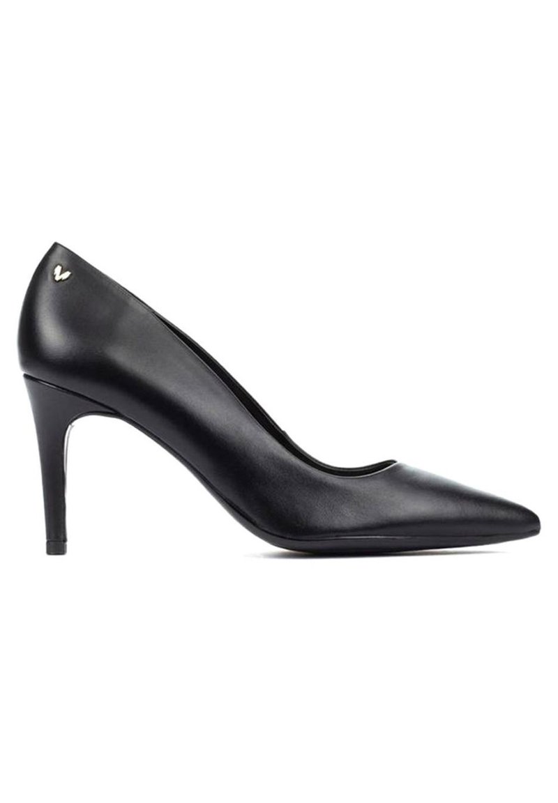 Zapato de charol negro de tacón alto con punta afilada, silueta esbelta y un pequeño acento metálico en el talón posterior. Textura suave.