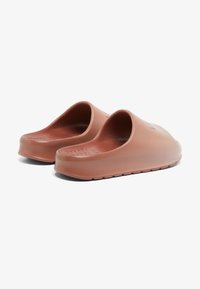 Sabots en caoutchouc brun avec un design à enfiler, bout rond, semelle texturée et talon plat. Finition lisse sans motifs ou accents visibles.