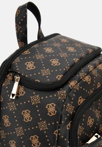 Zwarte rugzak met een patroonontwerp featuring bruine logo's, versierd met gouden hardware en een gestructureerd oppervlak. Ritsdetails zichtbaar.