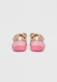Παιδικά παπούτσια με μπεζ επάνω μέρος, ροζ σόλα και λευκές λεπτομέρειες. Διαθέτουν λουράκι με αυτοκόλλητο για ασφαλές κλείσιμο και ανάγλυφο σχέδιο.