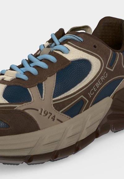 Baskets épaisses avec des panneaux marron, beige et bleu, des lacets bleu clair, une semelle texturée et un logo "Iceberg 1974" sur le côté.