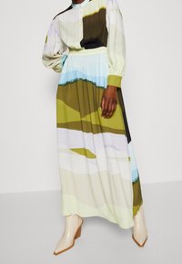 Mekko kevyestä kankaasta, jossa monivärinen maisemakuvio vihreän, sinisen ja beigen sävyissä; pitkät hihat, joustava vyötärö.