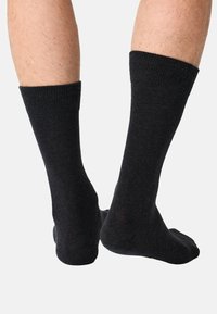 Sorte bomuldssokker med ribbede kanter, ankel-længde, der viser en glat tekstur og minimale syningsdetaljer. Velegnet til både afslappet og formelt brug.