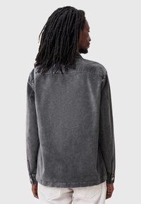 Chaqueta de denim gris para hombre con un corte relajado, puños de botón y un acabado de textura suave con un aspecto ligeramente desgastado.