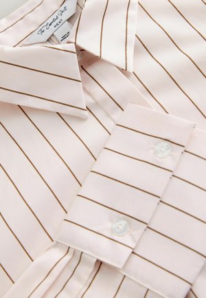 Vaaleanpunainen raidallinen paita, jossa on ohuita ruskeita viivoja, klassinen kaulus ja nappikiinnitys. Kangas on sileä ja teksturoitu.