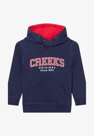Felpa blu navy con interno rosso, presenta una tasca frontale e la scritta bianca "CREEKS ORIGINAL Since 1974" sul petto.