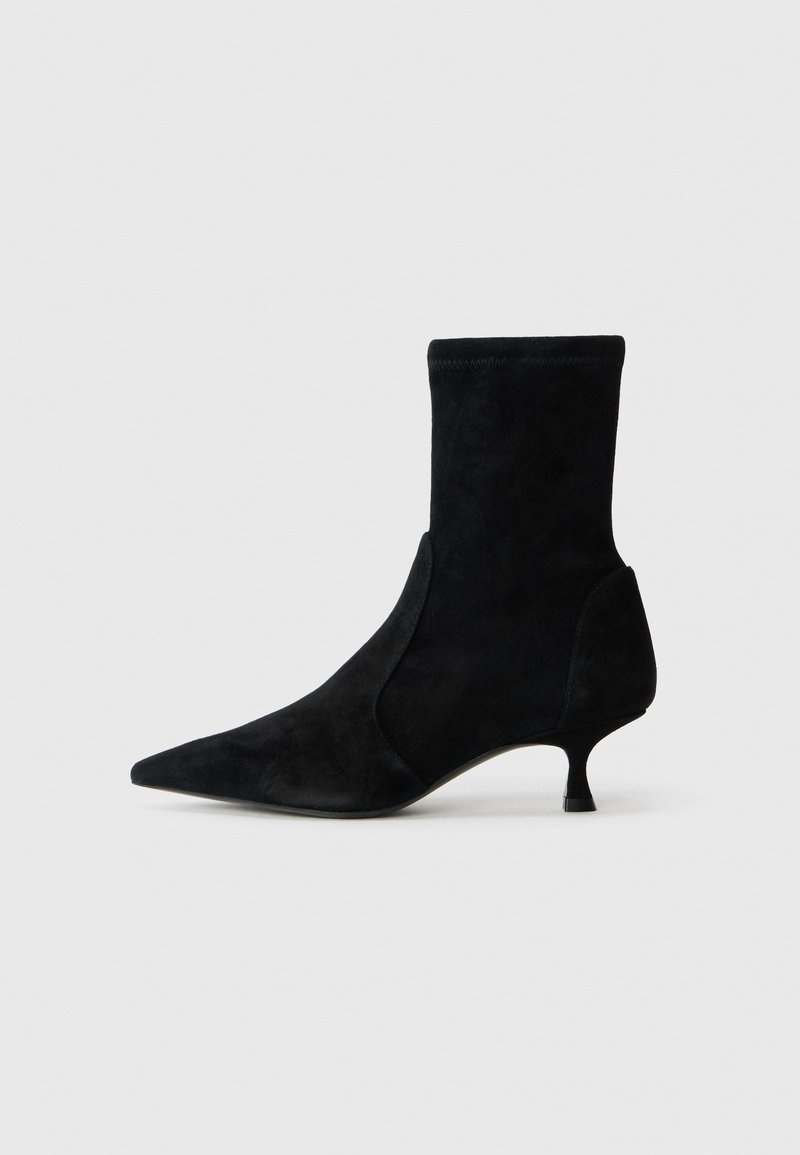 Svart mockaskinnsankleboots med spetsig tå och avsmalnande klack. Har ett åtsittande skaft och sömlös design utan synlig hårdvara.