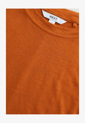 T-shirt arancione a maniche corte realizzato in cotone morbido. Presenta un collo a giro e un'etichetta con la scritta "NEXT" sulla parte posteriore del collo. Tessuto testurizzato.