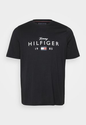 Melna kokvilnas T-krekls ar īsām piedurknēm, uz tā ir uzraksts baltā krāsā "Tommy HILFIGER" un neliels krāsains logo. Parasts piegriezums ar apaļu kakla izgriezumu.