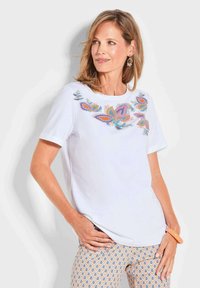 Witte t-shirt met korte mouwen en meerkleurige bloemenborduursels op de halslijn. Gladde stof, ontspannen pasvorm, gecombineerd met gemusterde broek.