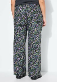 Bloemrijke wijde broek met een zwarte achtergrond, paarse en groene bloemenpatronen, gemaakt van een soepele stof en met een relaxte pasvorm.