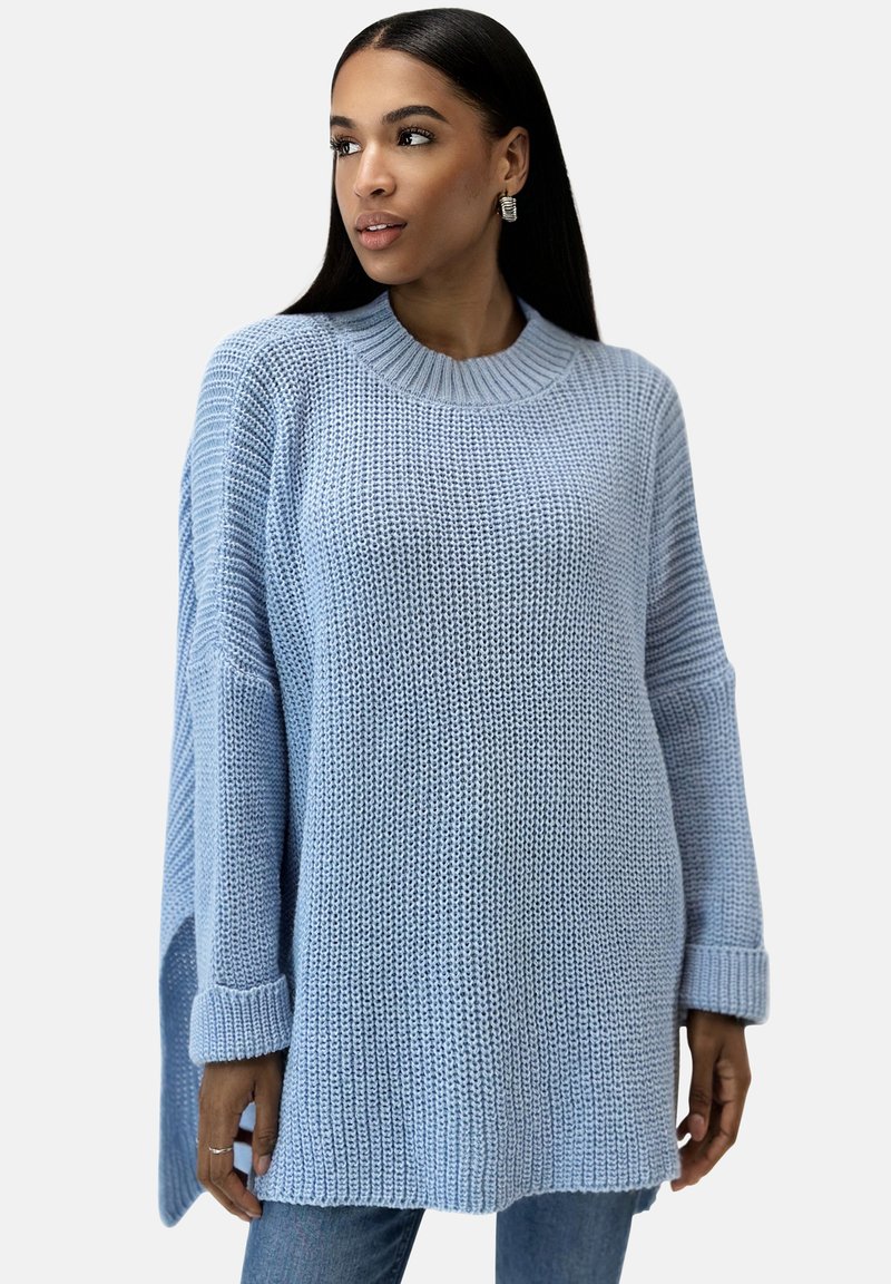 Suéter de punto azul claro con escote redondo, hombros caídos y puños de canalé. Presenta un ajuste holgado y oversized, y un patrón texturizado.