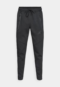 Μαύρα αθλητικά παντελόνια τζόγκινγκ μ ε ελαστική μέση και κορδόνι, δύο τσέπες με φερμουάρ στα πλαϊνά και διακριτικά λογότυπα. Κατασκευασμένα από μαλακό, υφασμένο υλικό.