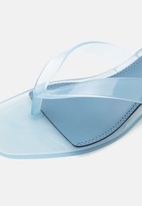 Διάφανη μπλε πλαστική σαγιονάρα με τετράγωνη μύτη και μαλακό μπλε πέλμα σε λευκό φόντο.