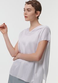 Lichtgewicht, wit, capuchonshirt met korte mouwen, voorzien van een gestructureerde stof en een relaxte pasvorm, die over de schouders en de rug valt.