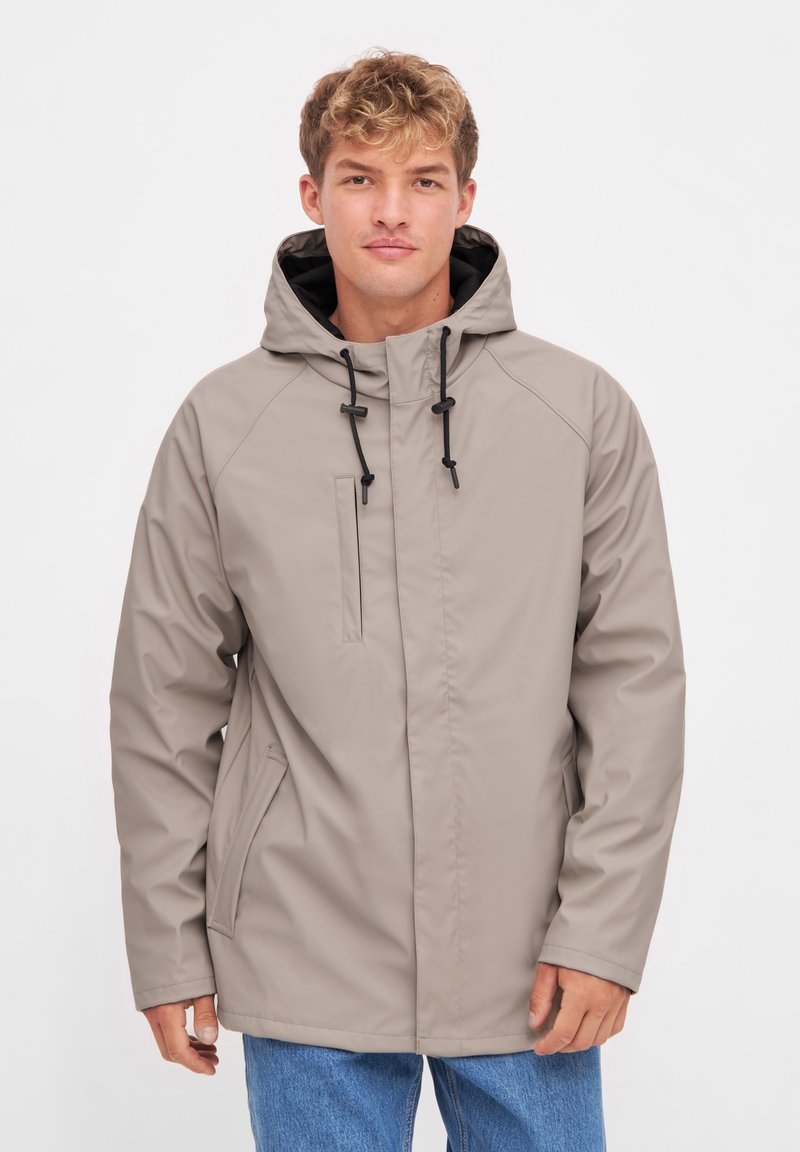 Beige water-resistant jacket with a hood, contrasting black drawstrings, front zip pocket, and side pockets. Smooth texture and casual fit.