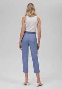 Light blue denim pants with an elastic waistband, rolled hems, and a smooth texture, paired with a white ribbed tank top.