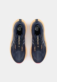Baskets de course navy avec une tige texturée, lacets noirs et semelle extérieure orange. Comprend des éléments de marque et des accents réfléchissants sur les côtés.