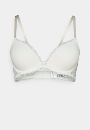 Light beige bra with smooth padded cups, lace detailing along the edges, and adjustable satin straps. Hook-and-eye closure at the back.